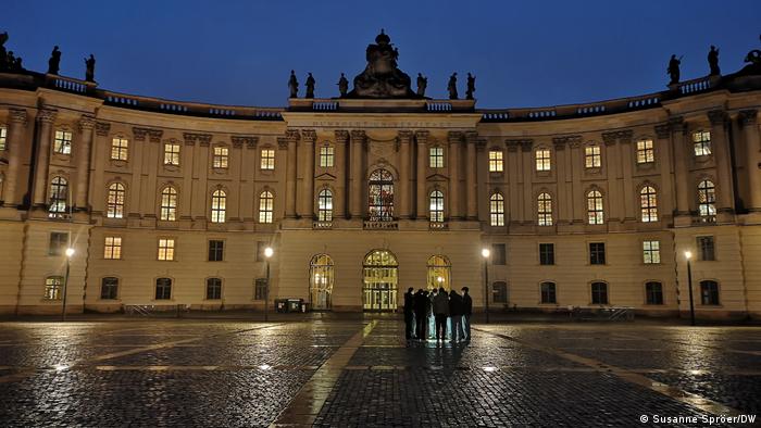 Eine Gruppe von Menschen steht am Denkmal der Bücherverbrennung auf dem Berliner Bebelplatz 
