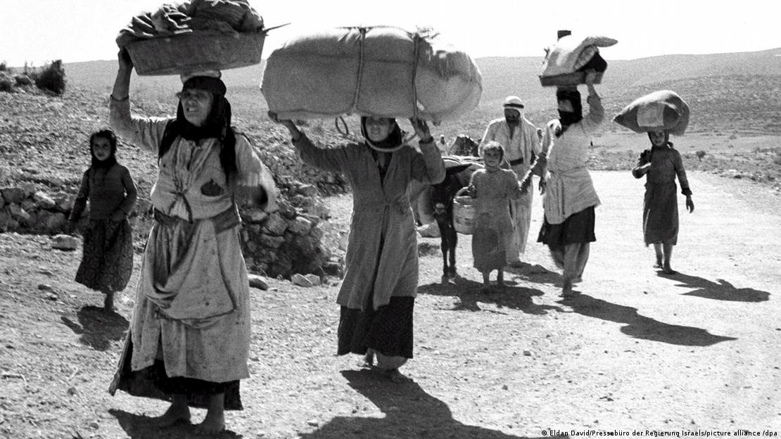 Palestinos em fuga carregam seus pertences em estrada de terra, em foto de 1948