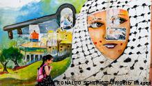 A Palestinian shcoolgirl walks past a Nakba mural in the refugee camp of Jenin in the occupied West Bank, on May 19, 2022. - Paletinians across the world and the occupied territories have been marking the 'Nakba' or 'catastrophe' which is a reference to the creation of the state Israel in 1948 as a result of which more than 760,000 Palestinians were pushed into exile or driven out of their homes. (Photo by RONALDO SCHEMIDT / AFP) (Photo by RONALDO SCHEMIDT/AFP via Getty Images)
