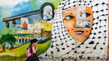 A Palestinian shcoolgirl walks past a Nakba mural in the refugee camp of Jenin in the occupied West Bank, on May 19, 2022. - Paletinians across the world and the occupied territories have been marking the 'Nakba' or 'catastrophe' which is a reference to the creation of the state Israel in 1948 as a result of which more than 760,000 Palestinians were pushed into exile or driven out of their homes. (Photo by RONALDO SCHEMIDT / AFP) (Photo by RONALDO SCHEMIDT/AFP via Getty Images)