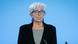 Christine Lagarde, woman with gray hair, blue glasses and blue earrings in dark jacket with gray top beneath, speaking at a microphone Christine Lagarde, woman with gray hair, blue glasses and blue earrings in dark jacket with gray top beneath, speaking at a microphone
