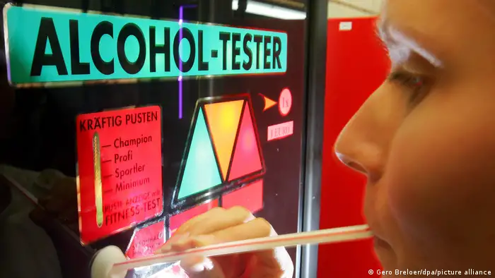 Woman blowing into a straw at an alcohol-tester station.