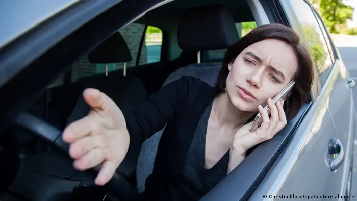 Woman speaking on her cell at the steering wheel.