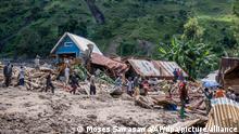 06.05.2023, Demokratische Republik Kongo, Nyamukubi: Menschen gehen an zerstörten Häusern vorbei. Nach schweren Überschwemmungen und Erdrutschen in der Demokratischen Republik Kongo ist die Zahl der Toten weiter gestiegen. Foto: Moses Sawasawa/AP/dpa +++ dpa-Bildfunk +++