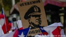 A man holds a sign depicting Gen. Augusto Pinochet who ruled Chile as a dictator from 1973 to 1990, during a protest called after the murder of police officer Daniel Palma, at Baquedano square in Santiago, Chile, Thursday, April 6, 2023. Palma's killing was the third murder of a police officer in the last 23 days. (AP Photo/Esteban Felix)