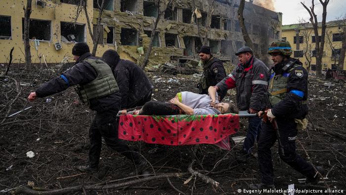Cuatro hombres trasladaron a una mujer embarazada, tras un bombardeo, en camilla, en Mariupol.