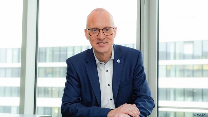 Dieter Westerkamp, VDI, sitzt vor einem Fenster. Sein Oberkörper ist zu sehen. Er trägt ein weißes Hemd, ein blaues Sakko und eine Brille.