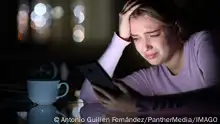 Sad teen crying checking phone in the night