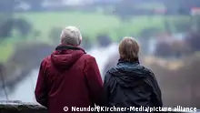 Ein Mann und eine Frau stehen auf einer Aussichtsplattform und schauen auf einen Fluss und eine Landschaft. Das ältere Paar scheint glücklich mit sich und der Welt zu sein. Für Rentner spielt die Altersversorgung mit ihren Rentenzahlungen eine große Rolle.