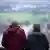 Duas pessoas adultas vistas pelas costas enquanto olham a paisagem