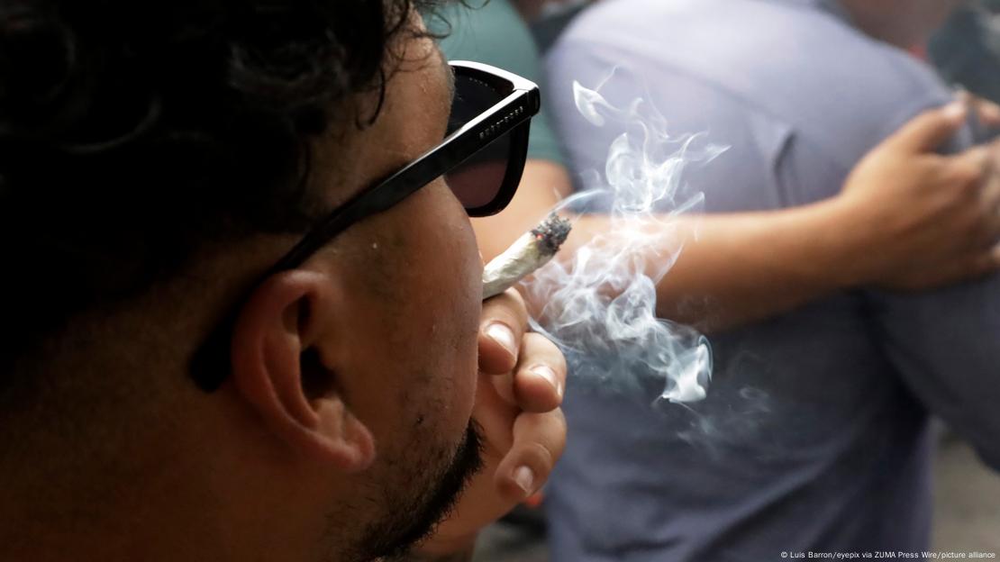 A man smokes a joint while wearing sunglasses