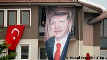 11.05.2023 *** A woman looks out of a building with a poster of Turkish President Tayyip Erdogan as supporters of Kemal Kilicdaroglu, presidential candidate of Turkey's main opposition alliance, gather during a rally ahead of the May 14 presidential and parliamentary elections, in Bursa, Turkey May 11, 2023. REUTERS/Murad Sezer