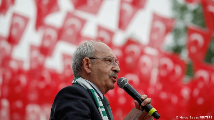 Kemal Kilicdaroglu, Präsidentschaftskandidat der Opposition steht auf der Bühne, in der Hand ein Mikro, hinter ihm viele rote Flaggen zu sehen. 