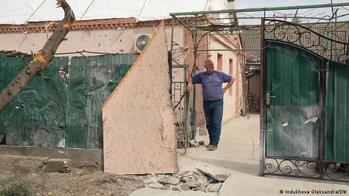 Ein Mann, Oleksandr, steht vor seinem beschädigten Haus