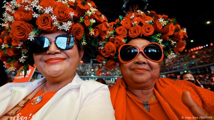 Dos mujeres con arreglos de rosas rojas en la cabeza.