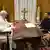 Wolodymyr Selenskyj sitzt am Schreibtisch Papst Franziskus gegenüber, auf dem hölzernen Tisch steht ein großes goldenes Kreuz