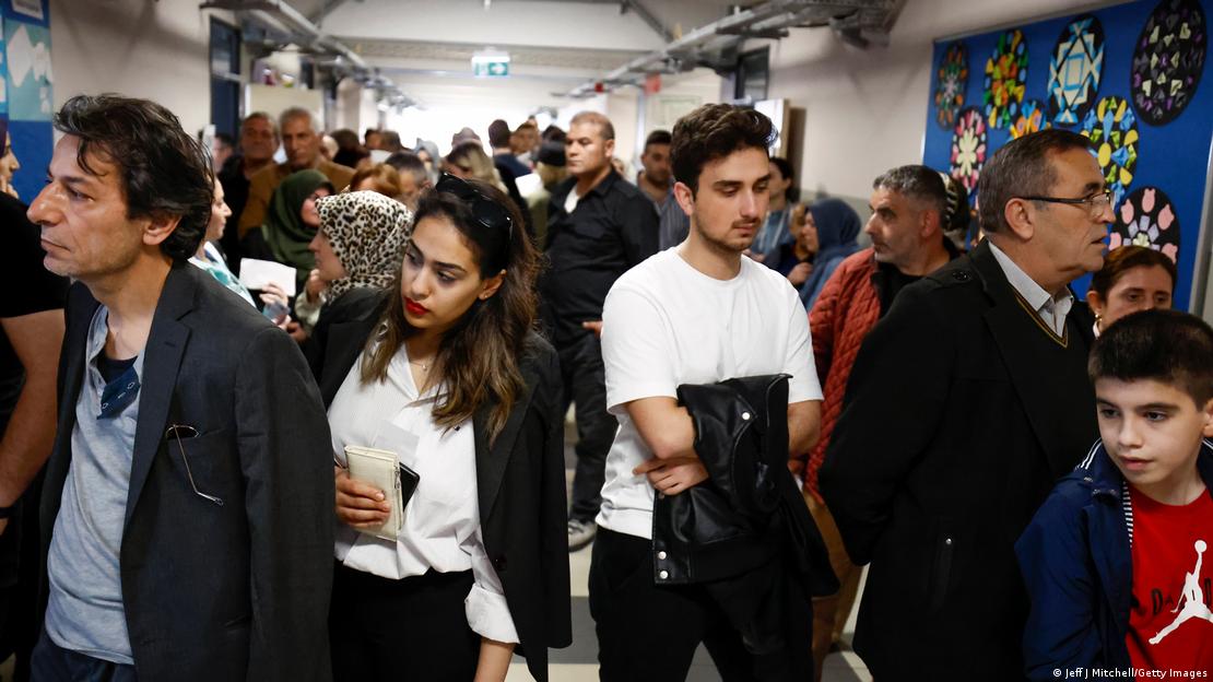 Pessoas em fila aguardam em um corredor Pessoas em fila aguardam em um corredor
