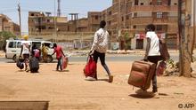 14/05/2023 TOPSHOT - People board a mini-bus as they evacuate southern Khartoum, on May 14, 2023. A month since Sudan's conflict erupted, its capital is a desolate war zone where terrorised families huddle in their homes, enduring desperate shortages of food and basic supplies, power blackouts, cash shortages and runaway inflation, as gun battles rage in the dusty, deserted streets outside. (Photo by AFP)