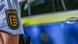 A Baden-Württemberg police crest on the arm of an officer with a police car in the background A Baden-Württemberg police crest on the arm of an officer with a police car in the background