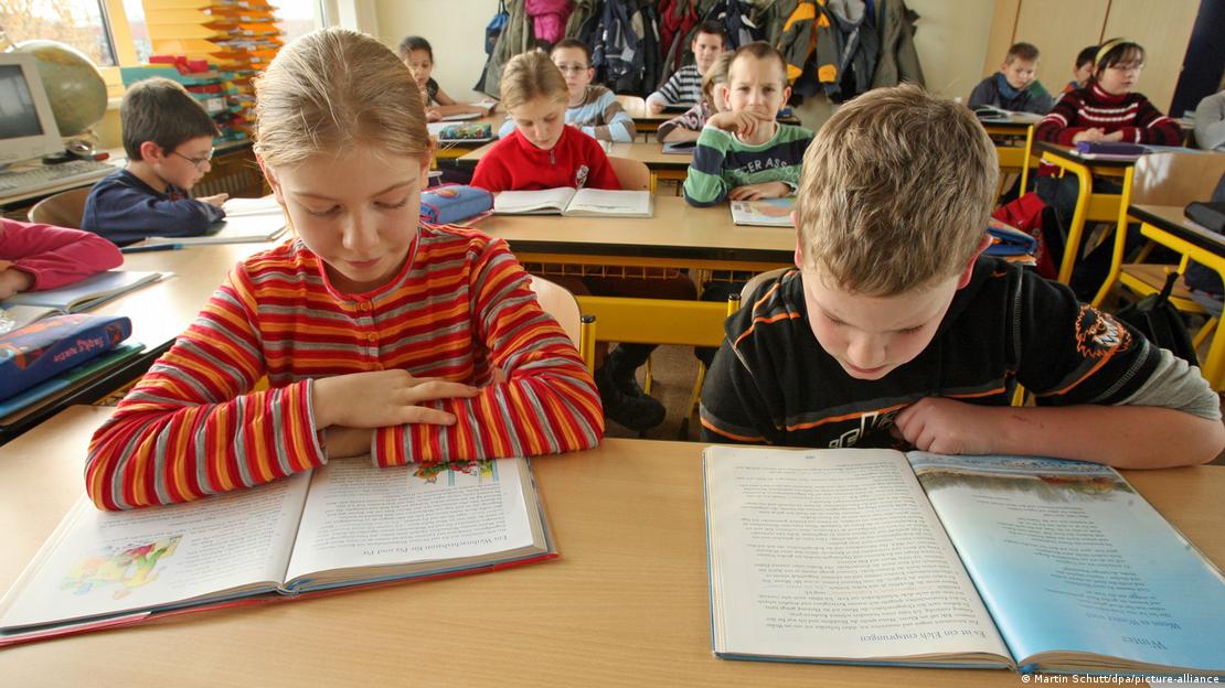 Almanya'da bir okulda sıralarında oturmuş, önlerindeki kitabı okuyan 4'üncü sınıf öğrencileri.