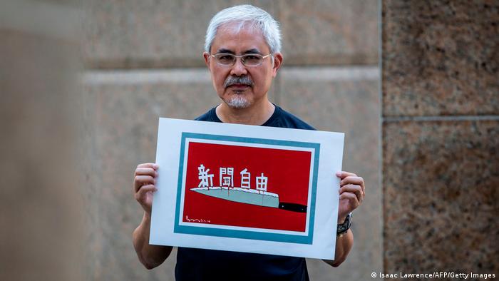 香港政治漫画家尊子（本名黄纪钧）在2020年6月20日拿著自己的作品，里头描绘香港的新闻自由状况。