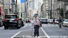 An elderly woman crosses a street in Tokyo on May 24, 2020. (Photo by CHARLY TRIBALLEAU / AFP) (Photo by CHARLY TRIBALLEAU/AFP via Getty Images)