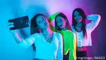 The lifestyle of friends partying in a disco with blue and pink neon lights taking a selfie for social networks *** der Lebensstil des Freunde partying