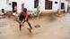 Una mujer busca barrer el lodo de una calle tras inundación en Lima Una mujer busca barrer el lodo de una calle tras inundación en Lima