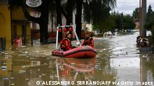 TOPSHOT - Volunteer firefighters ride their dinghy across a street flooded by the river Savio in the Ponte Vecchio district of Cesena, central eastern Italy, on May 17, 2023. Trains were stopped and schools were closed in many towns while people were asked to leave the ground floors of their homes and to avoid going out, and five people have died after the floodings across Italy's northern Emilia Romagna region. (Photo by Alessandro SERRANO / AFP) (Photo by ALESSANDRO SERRANO/AFP via Getty Images)