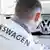 Сотрудник завода Volkswagen в Калуге приклеивает логотип VW на автомобиль