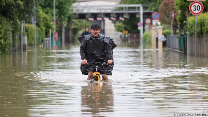Ein Mann radelt durch Wassermassen nach Überschflutungen in Lugo, Italien