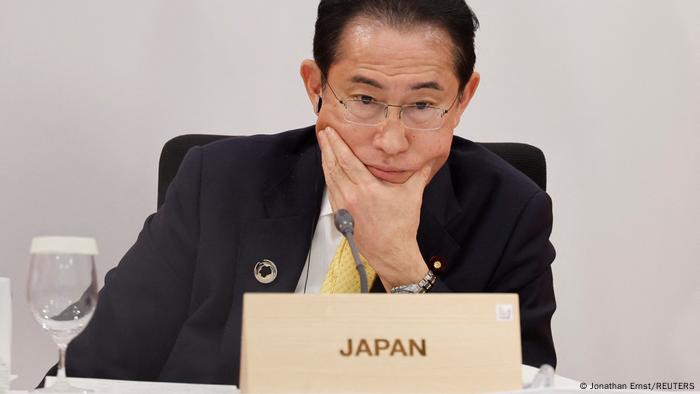 El primer ministro japonés, con gesto pensativo, en su mesa con el cartel de representante de Japón durante la reunión.