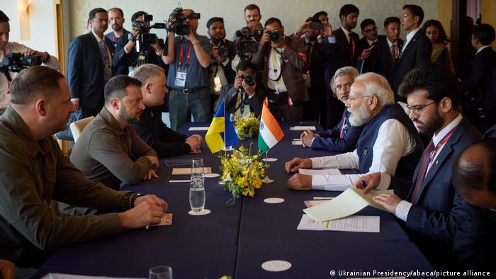  El presidente ucraniano, sentado a la mesa frente a su homólogo indio, con las banderolas de sendos países y multitud de camarógrafos al fondo.