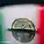 An Italian euro sinks in water with an Italian flag reflected on the surface