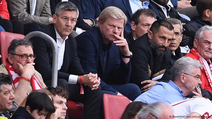 Bayern-Präsident Hainer, Vorstandschef Kahn und Sportvorstand Salihamidzic sitzen mit nachdenklicher Miene auf der Tribüne des Mainzer Stadions.