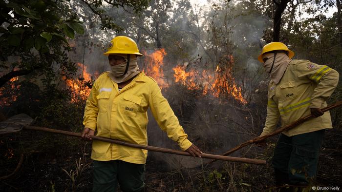 Zwei maskierte Feuerwehrleute vor einem Buschbrand