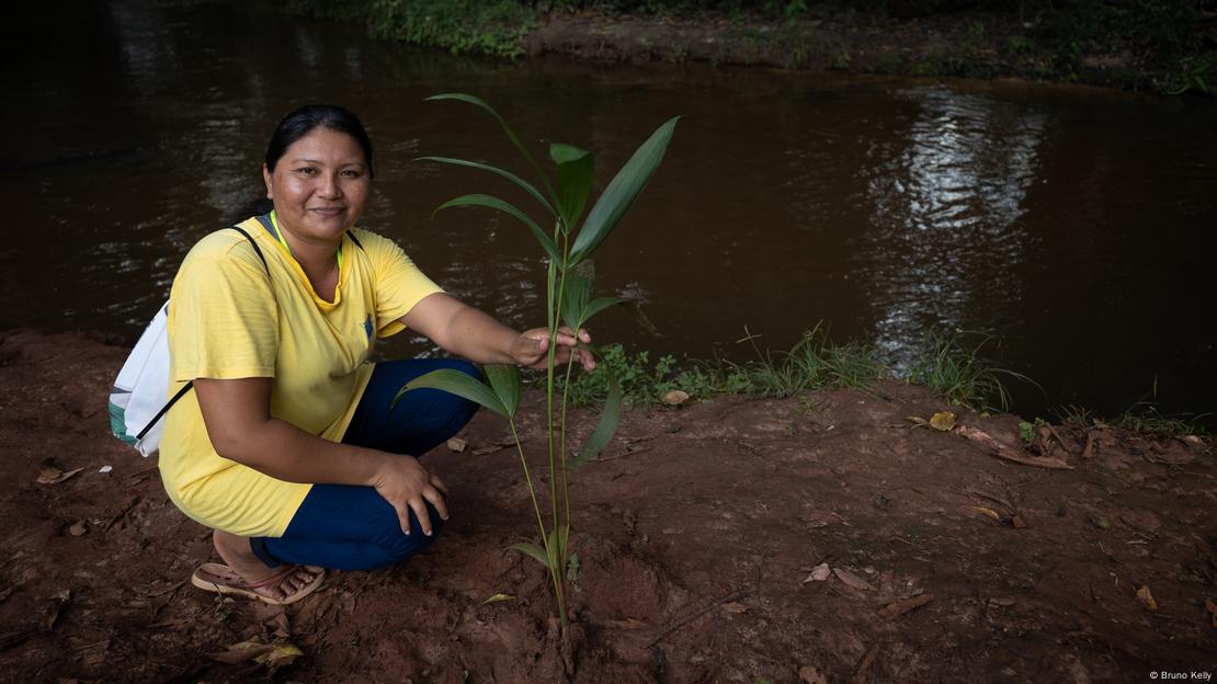 Indígena Marlucia Aponajé ao lado de muda de planta