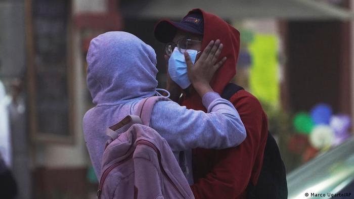 Пара в толстовках и масках, чтобы защитить себя от пепла от вулкана Попокатепетль, обнимается в Атлиско, Мексика.