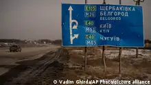 ARCHIV 24/02/2023 *** A car drives by bullet and shrapnel riddled road sign on the road to the Russian city of Belgorod, near the place where the first clashes between the Russian and Ukrainian forces took place a year ago, in Kharkiv, Ukraine, Friday, Feb. 24, 2023. Ukraine's leader pledged Friday to push for victory in 2023 as he and other Ukrainians marked the somber anniversary of the Russian invasion that upended their lives and Europe's security. (AP Photo/Vadim Ghirda)