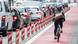 Ciclista na via de bicicletas ao lado de uma fila de carros engarrafados na rua Ciclista na via de bicicletas ao lado de uma fila de carros engarrafados na rua