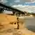 Український військовий ловить рибу біля зруйнованого мосту через річку Оскіл, околиці села Підвисоке Харківської області, травень 2023 року