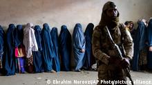 A Taliban fighter stands guard as women wait to receive food rations distributed by a humanitarian aid group, in Kabul, Afghanistan, Tuesday, May 23, 2023. (AP Photo/Ebrahim Noroozi)