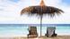Two chairs under a sun umbrella next to the water. Two chairs under a sun umbrella next to the water.