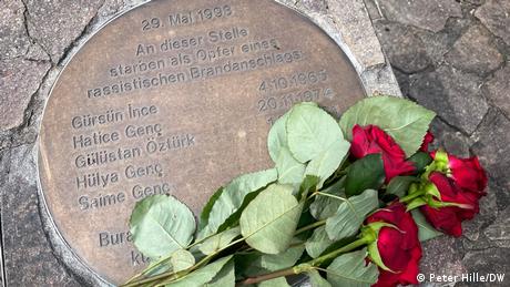 Eine Platte im Boden mit den Namen der Opfer des Brandanschlags von Solingen und mehrere Rosen (Quelle: Peter Hille/DW)