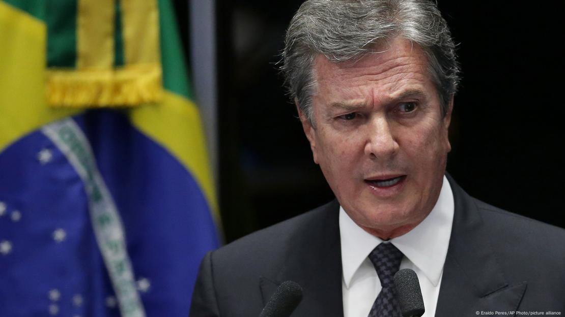 Ex-presidente Fernando Collor e uma bandeira do Brasil ao fundo