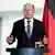 German Chancellor Olaf Scholz on the podium with flags behind him