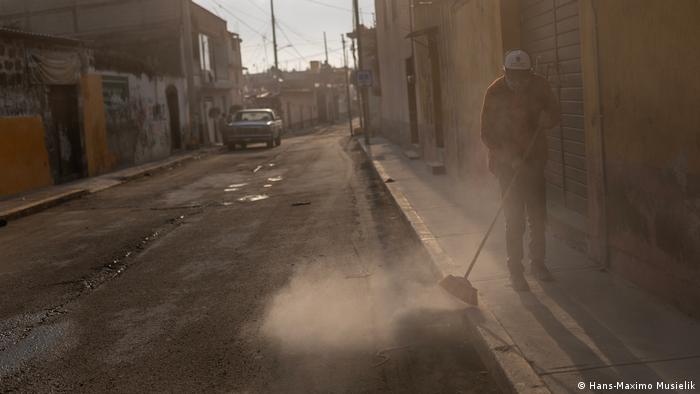 Calle cubierta de ceniza y un hombre barriéndola en México Calle cubierta de ceniza y un hombre barriéndola en México