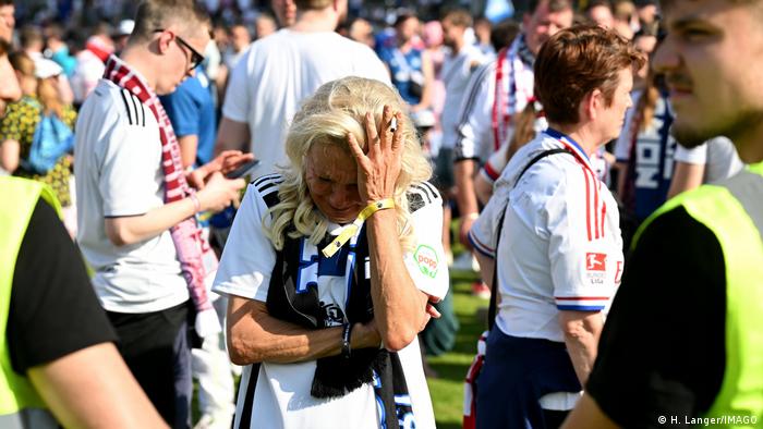 Fans des Hamburger SV stehen enttäuscht und traurig auf dem Spielfeld des SCV Sandhausen