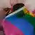 Ein Mann versteckt sich hinter einer Regenbogenfahne 
