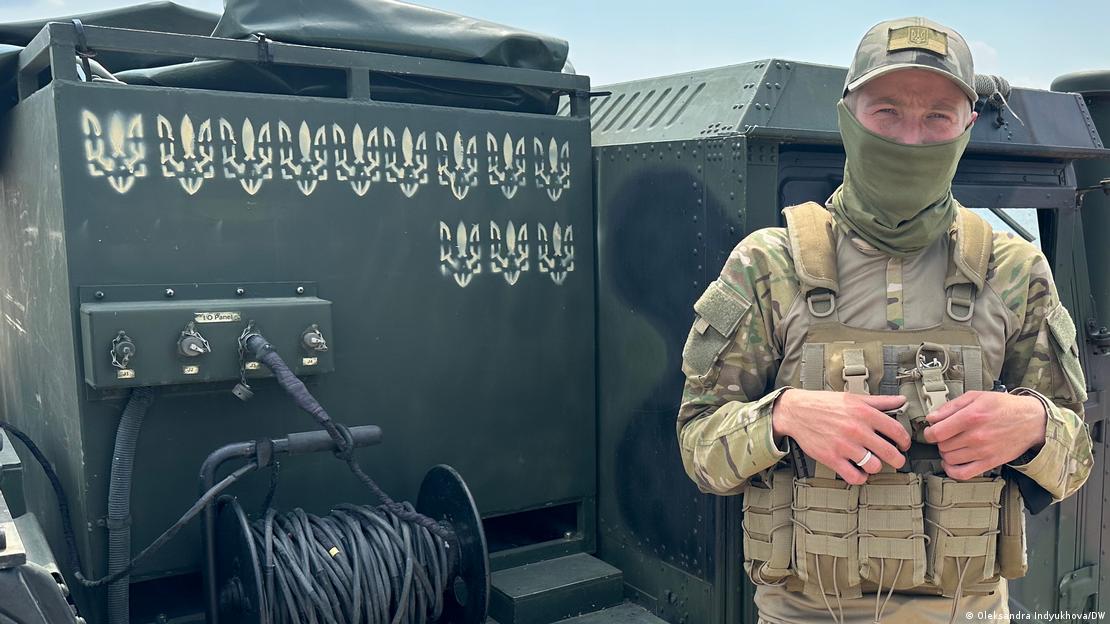 Soldado ucraniano ao lado de veículo militar com síimbolo nacional